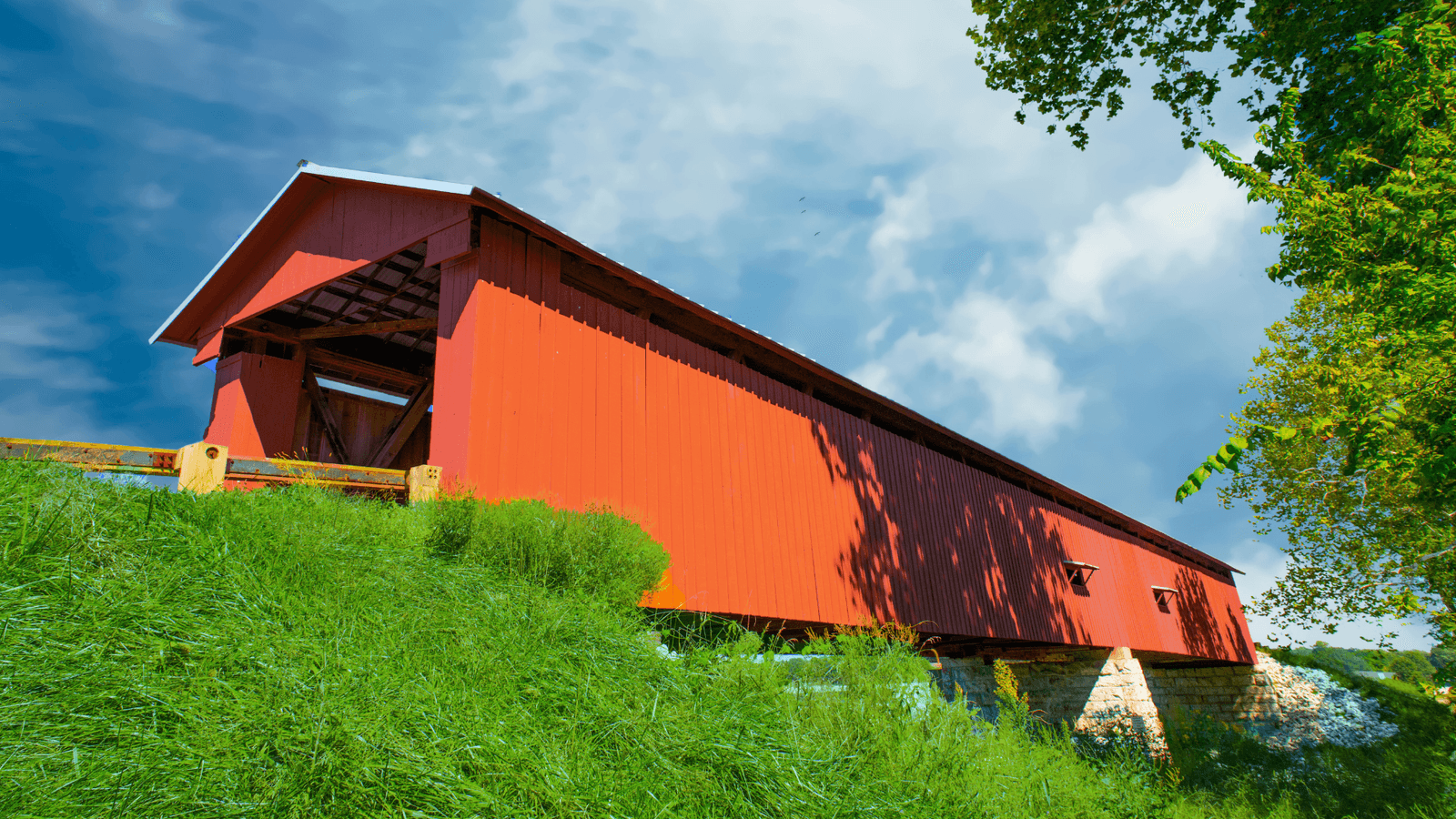 A red covered bridge in rural Indiana on a summer day.